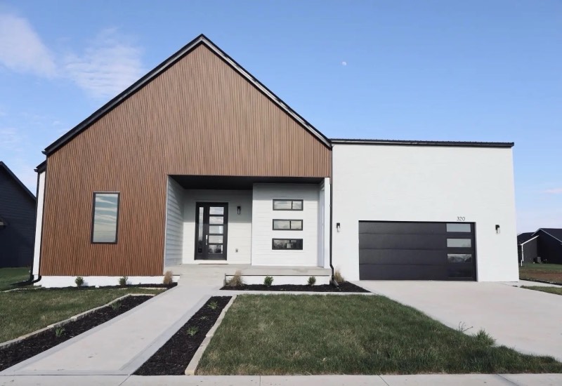Completed modern farmhouse custom home with vertical wood siding, white brick and black windows in Central Iowa