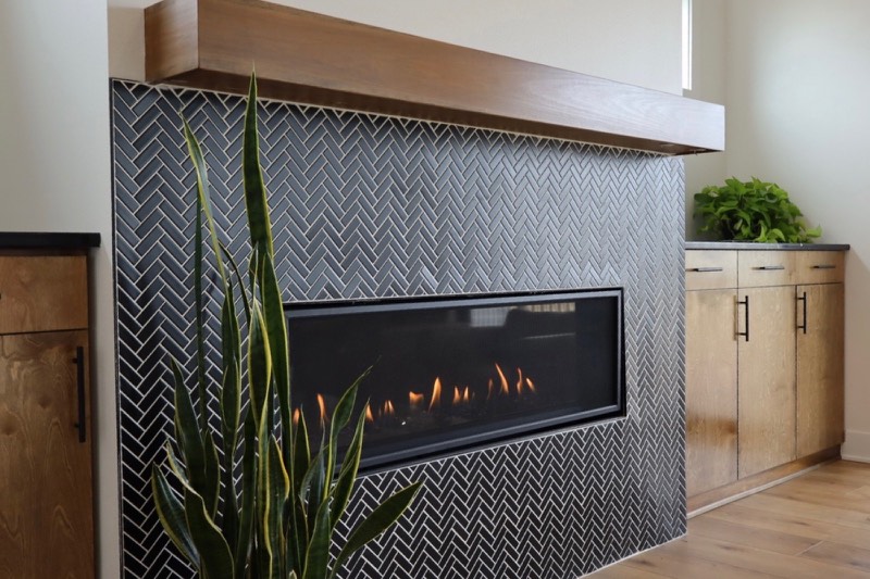 Black herringbone tile fireplace with a stained solid timber mantel and white oak cabinetry