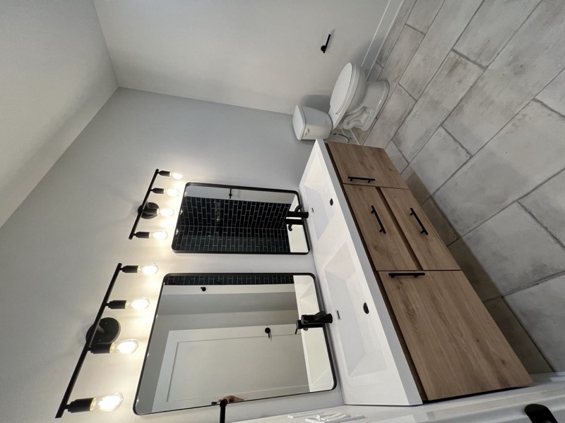Guest bathroom with a floating double vanity, integrated basins, black mirrors and Edison bar lighting