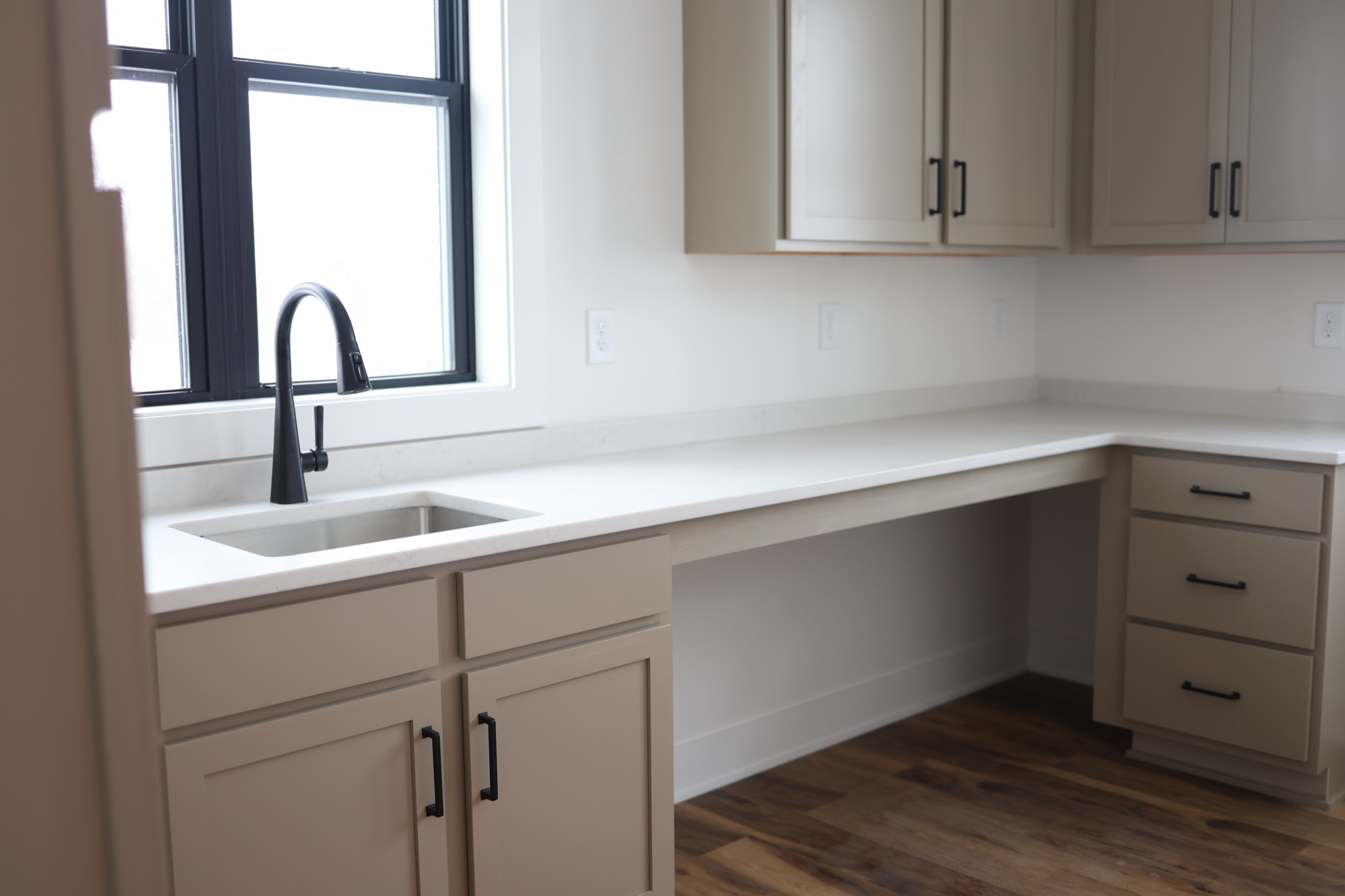 Laundry room with a long quartz folding counter, undermount sink and built-in desk nook in a completed Stone + Timber custom home