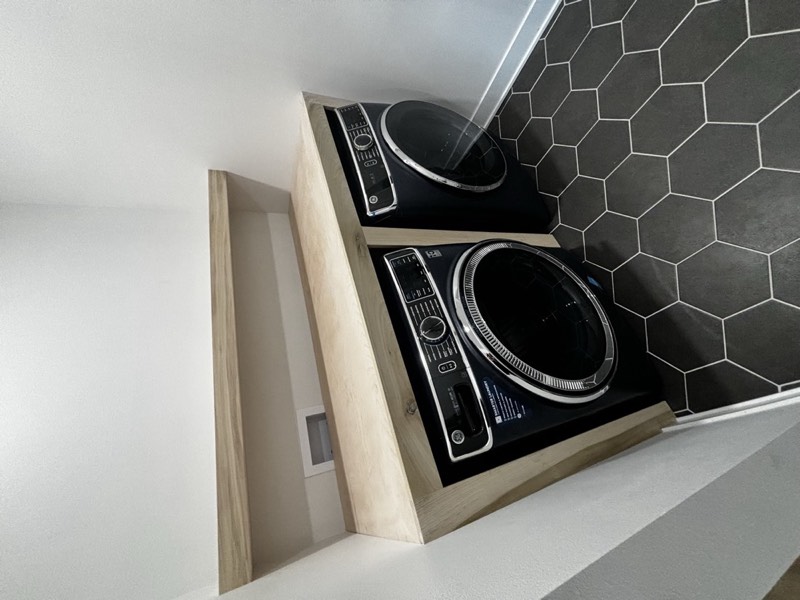 Laundry with a solid timber folding counter over the washer and dryer, a matching shelf above and hex floor tile