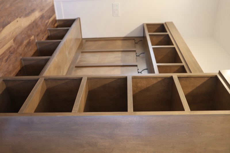 Custom stained mudroom lockers with a bench, cubbies, iron hooks and open shelving