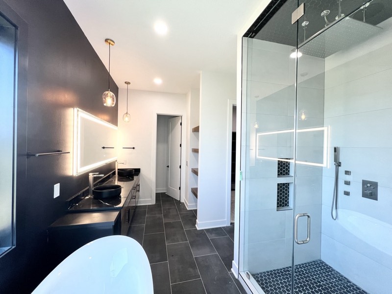 Primary bath with a glass steam shower, rain head, body sprays, backlit mirror and black floating vanity