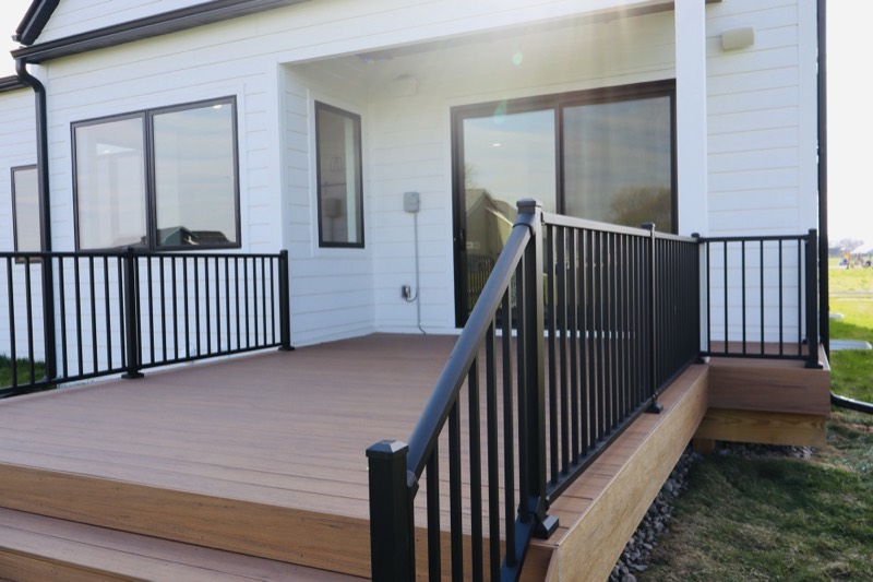 Composite deck with black aluminum railing against white lap siding on a Central Iowa home