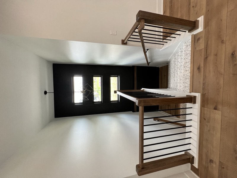 Stair landing with oak handrails, iron balusters and a black accent wall around stacked windows
